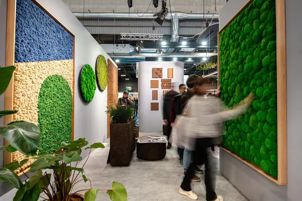 Människor tittar på moderna gröna konstinstallationer i ett galleri.